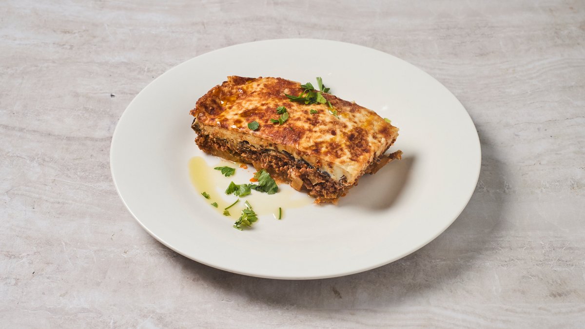 Homemade traditional Greek moussaka with golden béchamel and parsley at Cookaki Athens